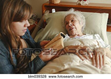 Granddaughter reading to grandmother in bed View Large Photo Image Stock Photo - Granddaughter reading to grandmother in bed. Fotosearch