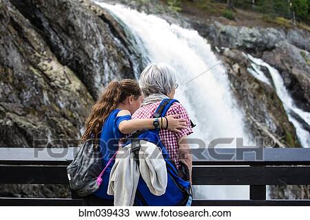 Stock Image - Grandmother and granddaughter admiring waterfall. Fotosearch