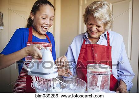 Stock Photograph - Grandmother and granddaughter baking in kitchen. Fotosearch