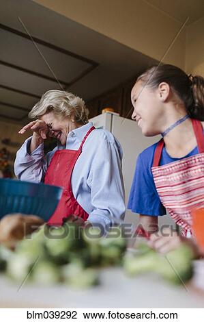Stock Image - Grandmother and granddaughter cooking in kitchen. Fotosearch