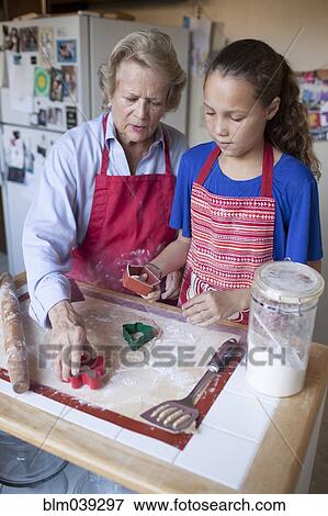 Grandmother and granddaughter cutting cookies from dough View Large Photo Image Stock Photo - Grandmother and granddaughter cutting cookies from dough. Fotosearch