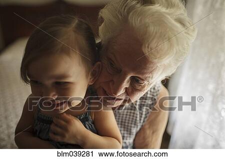 Stock Image - Grandmother and granddaughter hugging on bed. Fotosearch