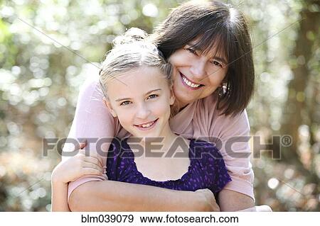 Stock Photo - Grandmother and granddaughter hugging in forest. Fotosearch