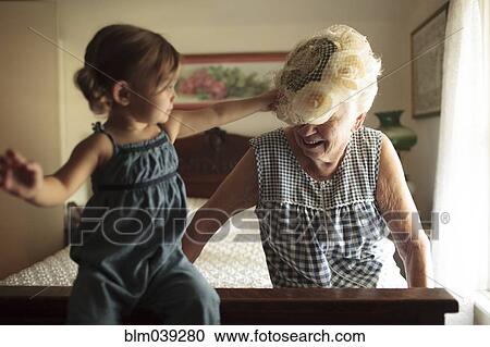 Stock Image - Grandmother and granddaughter playing on bed. Fotosearch
