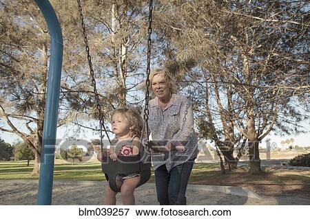 Grandmother pushing granddaughter on swing at playground View Large Photo Image Stock Photo - Grandmother pushing granddaughter on swing at playground. Fotosearch
