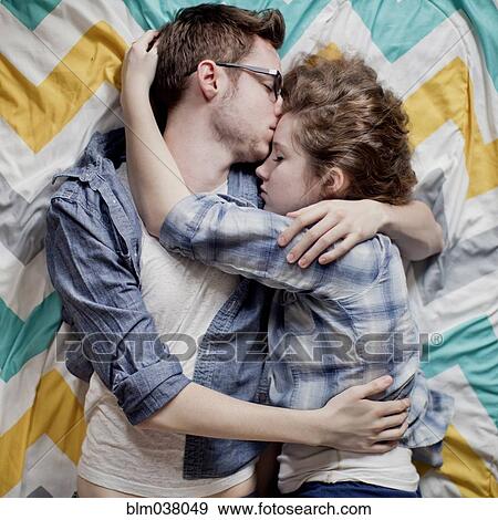 Stock Photo - High angle view of cuddling couple on bed. Fotosearch