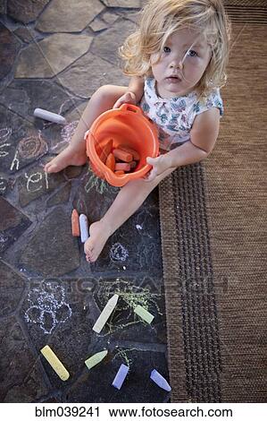 Stock Image - High angle view of girl drawing with chalk on tile. Fotosearch