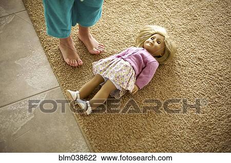 Stock Image - High angle view of teenage girl standing over doll. Fotosearch