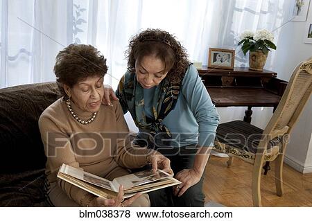 Stock Photo - Hispanic mother and daughter looking at photo album. Fotosearch