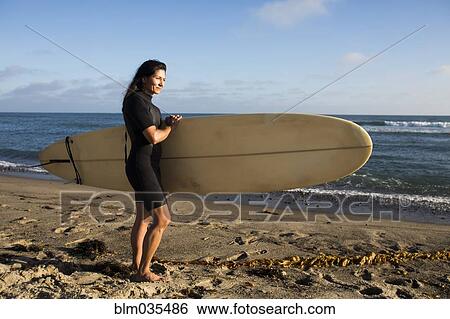 Hispanic surfer carrying surfboard on beach View Large Photo Image Stock Photograph - Hispanic surfer carrying surfboard on beach. Fotosearch