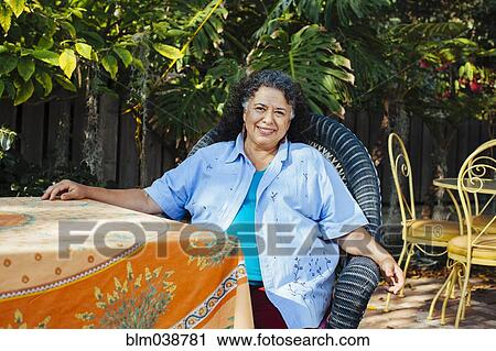 Stock Image - Hispanic woman relaxing in backyard. Fotosearch