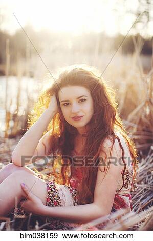 Stock Photo - Hispanic woman sitting in tall grass in field. Fotosearch