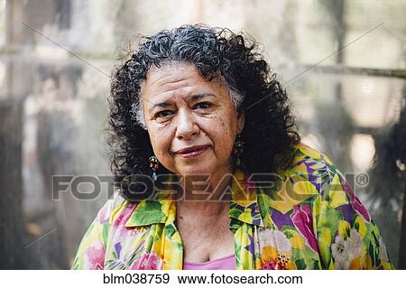 Stock Photo - Hispanic woman smiling in smoky backyard. Fotosearch
