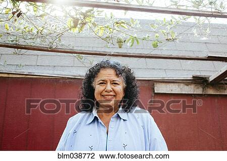 Stock Image - Hispanic woman smiling under transparent roof. Fotosearch