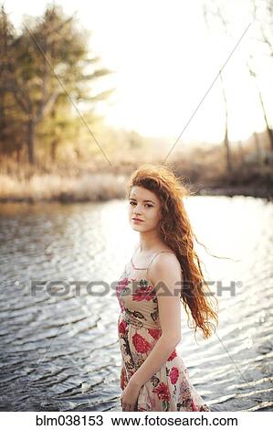 Stock Image - Hispanic woman standing in rural lake. Fotosearch