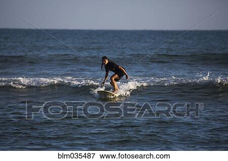 Stock Photo - Hispanic woman surfing in ocean. Fotosearch