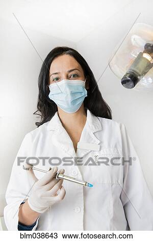 Indian dentist holding syringe by light View Large Photo Image Stock Image - Indian dentist holding syringe by light. Fotosearch