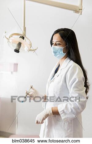 Indian dentist holding syringe near lamp View Large Photo Image Stock Photography - Indian dentist holding syringe near lamp. Fotosearch