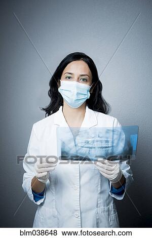 Indian dentist in face mask examining x-rays View Large Photo Image Stock Photo - Indian dentist in face mask examining x-rays. Fotosearch