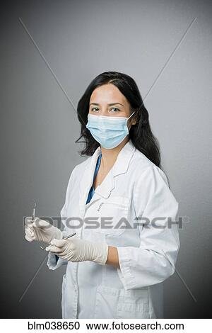 Indian dentist in surgical mask holding tools View Large Photo Image Stock Image - Indian dentist in surgical mask holding tools. Fotosearch