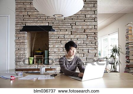 Stock Photo - Japanese woman paying bills on laptop. Fotosearch