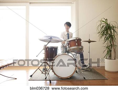 Stock Photo - Japanese woman playing drums in living room. Fotosearch