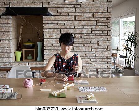 Stock Image - Japanese woman wrapping gifts. Fotosearch