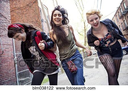 Stock Image - Laughing friends playing on city sidewalk. Fotosearch