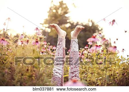 Stock Image - Legs of girl sticking up in wildflowers. Fotosearch