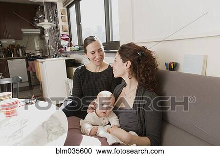 Lesbian couple cradling baby daughter on sofa View Large Photo Image Stock Image - Lesbian couple cradling baby daughter on sofa. Fotosearch