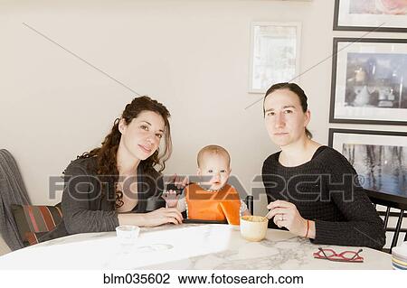 Lesbian couple feeding baby daughter at table View Large Photo Image Stock Image - Lesbian couple feeding baby daughter at table. Fotosearch
