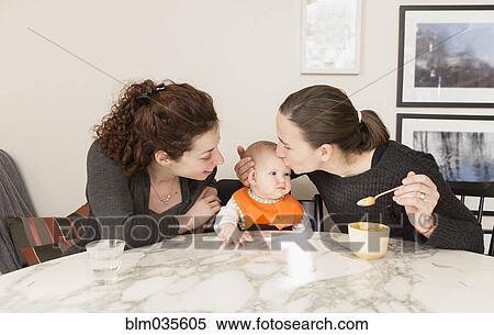 Lesbian couple feeding baby daughter at table View Large Photo Image Stock Photography - Lesbian couple feeding baby daughter at table. Fotosearch