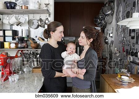 Lesbian couple holding baby daughter in kitchen View Large Photo Image Stock Photo - Lesbian couple holding baby daughter in kitchen. Fotosearch