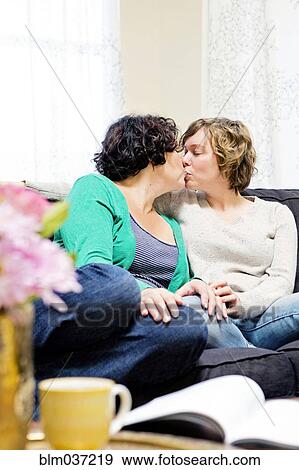 Lesbian couple kissing on sofa in living room View Large Photo Image Stock Photo - Lesbian couple kissing on sofa in living room. Fotosearch