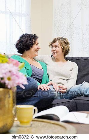 Lesbian couple relaxing on sofa in living room View Large Photo Image Stock Photo - Lesbian couple relaxing on sofa in living room. Fotosearch