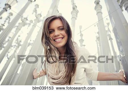 Stock Image - Low angle view of woman leaning on columns. Fotosearch