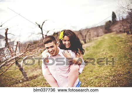 Stock Photograph - Man carrying girlfriend piggyback in vineyard. Fotosearch