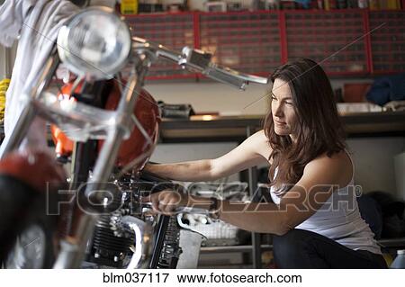 Stock Photo - Mechanic repairing motorcycle in garage. Fotosearch