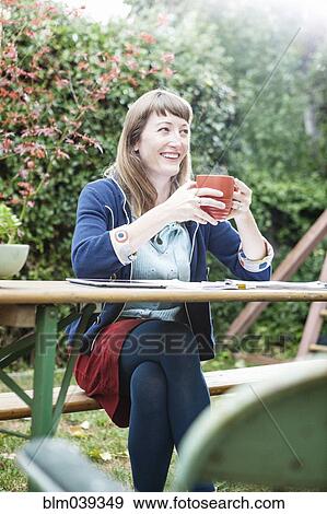 Stock Photo - Mixed race businesswoman drinking coffee in backyard. Fotosearch