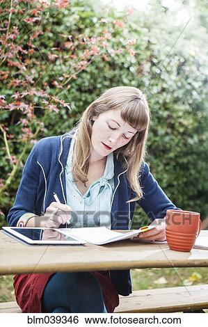 Stock Photograph - Mixed race businesswoman examining paperwork outdoors. Fotosearch