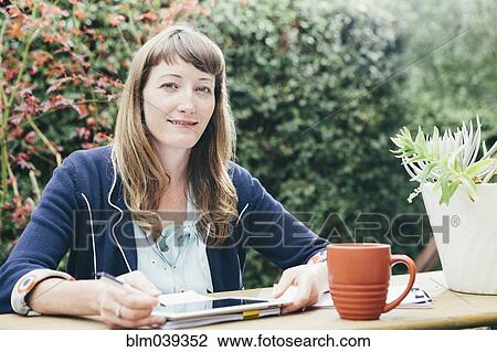 Stock Image - Mixed race businesswoman using digital tablet in backyard. Fotosearch