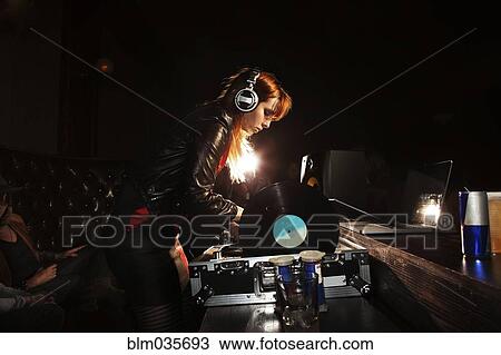 Stock Image - Mixed race DJ playing records at nightclub. Fotosearch