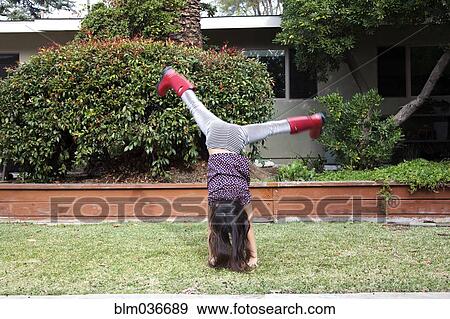 Stock Photo - Mixed race girl doing cartwheels in backyard. Fotosearch