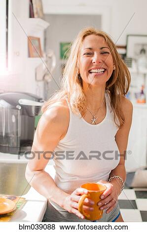 Mixed race woman drinking coffee in kitchen View Large Photo Image Stock Photo - Mixed race woman drinking coffee in kitchen. Fotosearch