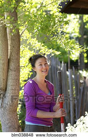 Stock Photo - Mixed race woman holding pole in garden. Fotosearch