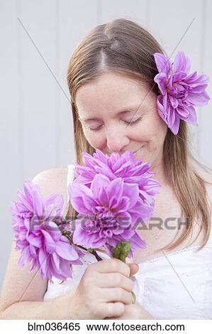 Stock Photography - Mixed race woman smelling flowers. Fotosearch