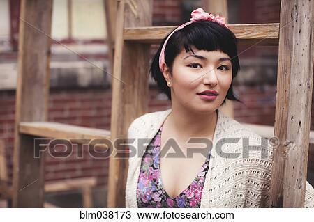 Stock Image - Mixed race woman standing near wooden frame. Fotosearch