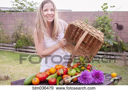 Stock Photo - Mixed race woman with basket of vegetables and flowers. Fotosearch