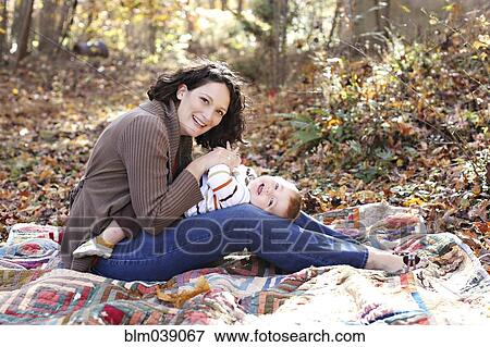Stock Photo - Mother and baby daughter playing on blanket in forest. Fotosearch