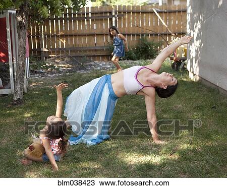 Stock Image - Mother and daughter dancing in backyard. Fotosearch